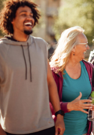 Two people walking outdoors together, smiling and enjoying a casual conversation.